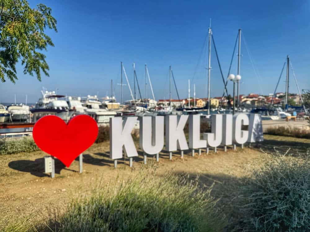 A welcoming sign in Kukljica, with the harbour visible just behind